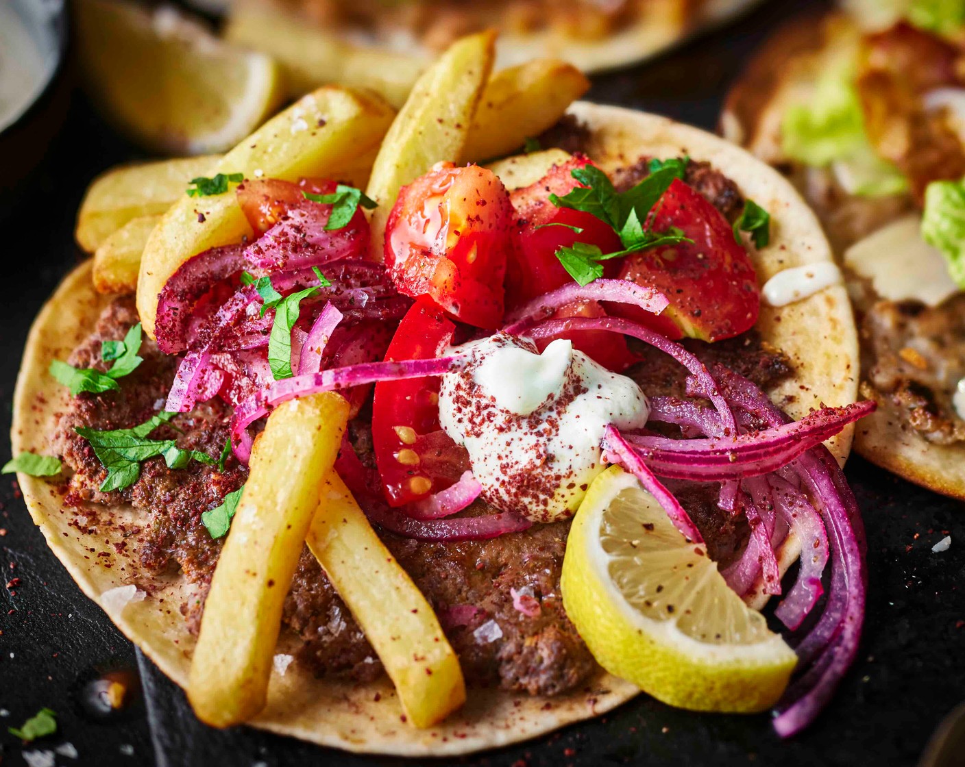 step 8 Top each taco with yogurt sauce, sumac onions, diced tomato (1) and chips. Finish with extra sumac, chopped parsley (1 handful) and the remaining lemon (1) cut into wedges to serve.