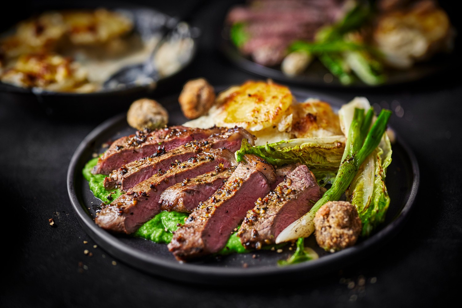 Grilled beef sirloin with pommes dauphinoise, pea purée and crispy garlic mushrooms