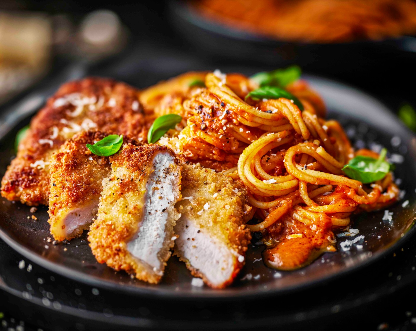 step 5 Divide the spaghetti between the plates. Top with the pork Milanese, scatter over the basil (1 handful) and finish with extra parmesan, black pepper and lemon wedges for squeezing.