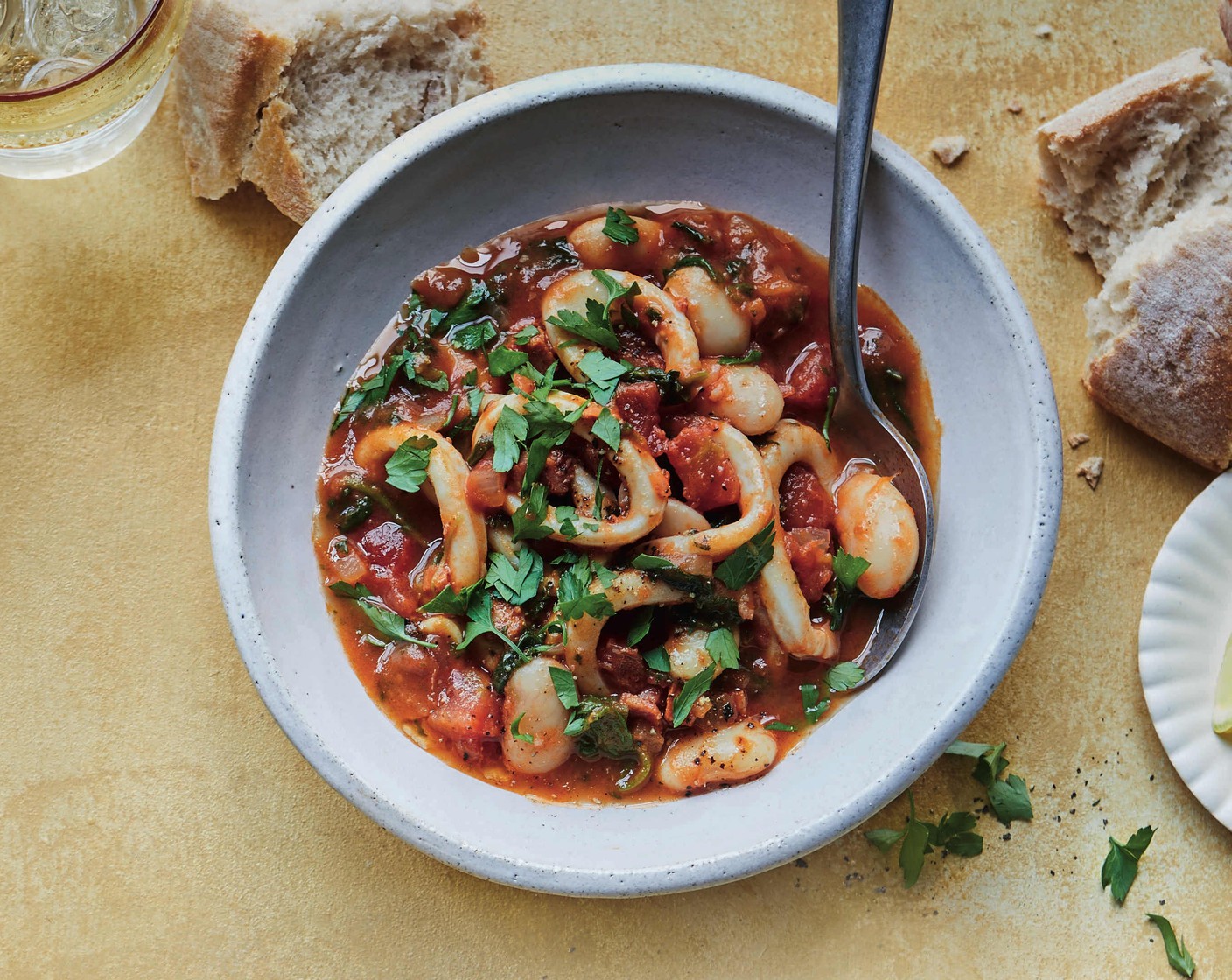 step 3 Add the butter beans (1 tin) and spinach (100 g) to the pan and simmer for 1 minute, then add the squid (200 g), cover and cook for 3-4 minutes. Serve the stew scattered with the parsley (1 handful), with lemon wedges (1) and crusty bread (to taste) alongside.