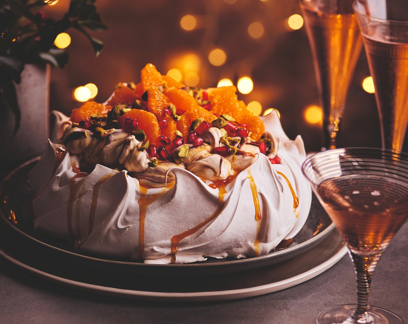 step 10 Place the pavlova onto a serving plate and spoon the cream into the middle. Arrange the clementine slices, pomegranate seeds (2 tbsp) and chopped pistachios (40 g) on top. Drizzle over the caramel syrup and finish with chocolate curls.