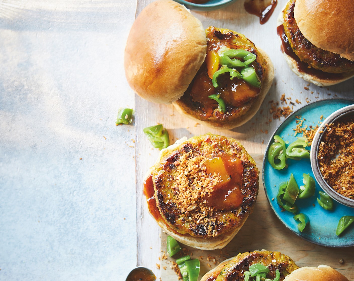 step 4 When the burgers are ready, slice open the buns (4). Spread 1 tsp mango chutney (4 tsp) and 1 tsp dry garlic chutney onto the base of each, then add the burgers. Top each with 1 tsp tamarind and chilli ketchup (4 tsp) and a scattering of chillies, then close the buns. Serve with a fresh green salad and more mango chutney and tamarind and chilli ketchup on the side, if you like.