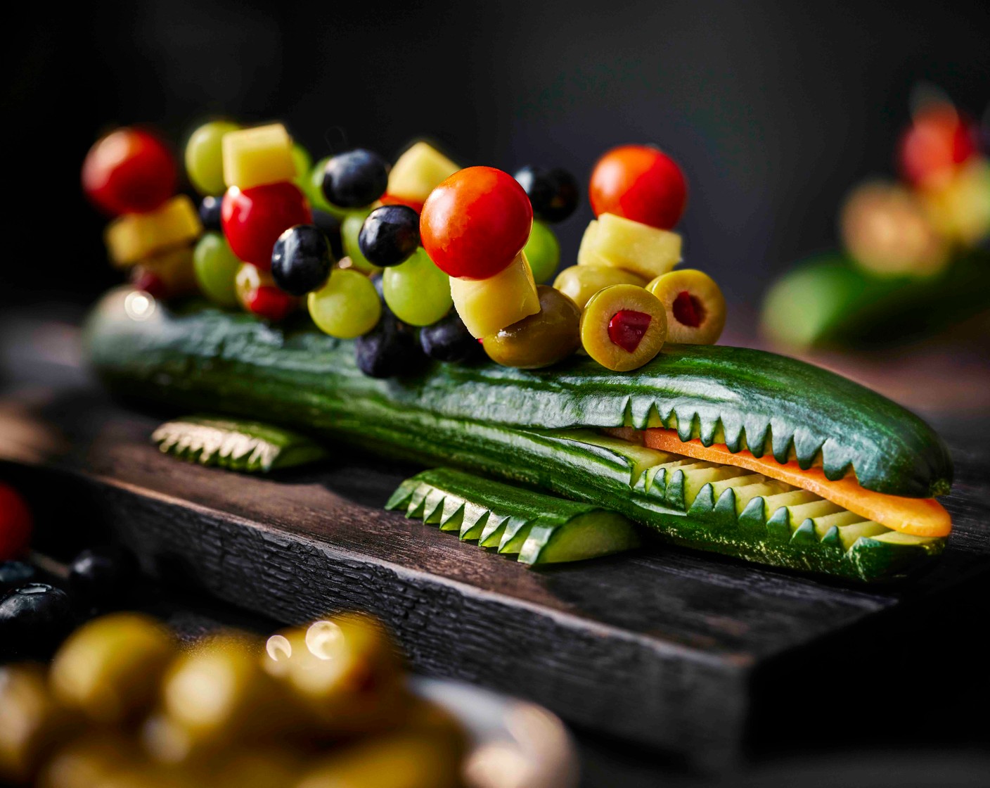 step 7 Slice one olive to give you two eye-shaped discs. Pop each onto a cocktail stick and pop onto the crocodile to look like eyes. Serve.
