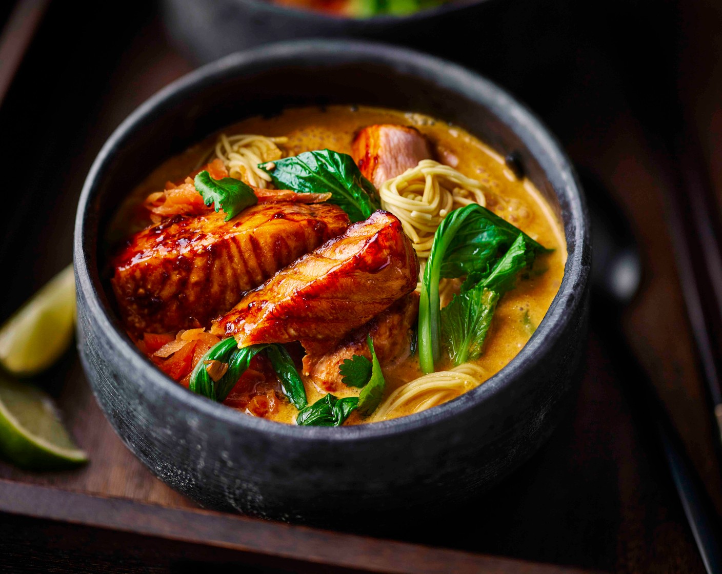 step 5 Divide the noodles between two bowls, then spoon over the broth. Top with the cooked salmon fillet. Garnish with chopped coriander (1 handful), a wedge of lime (1) and a drizzle of soy sauce (to taste).