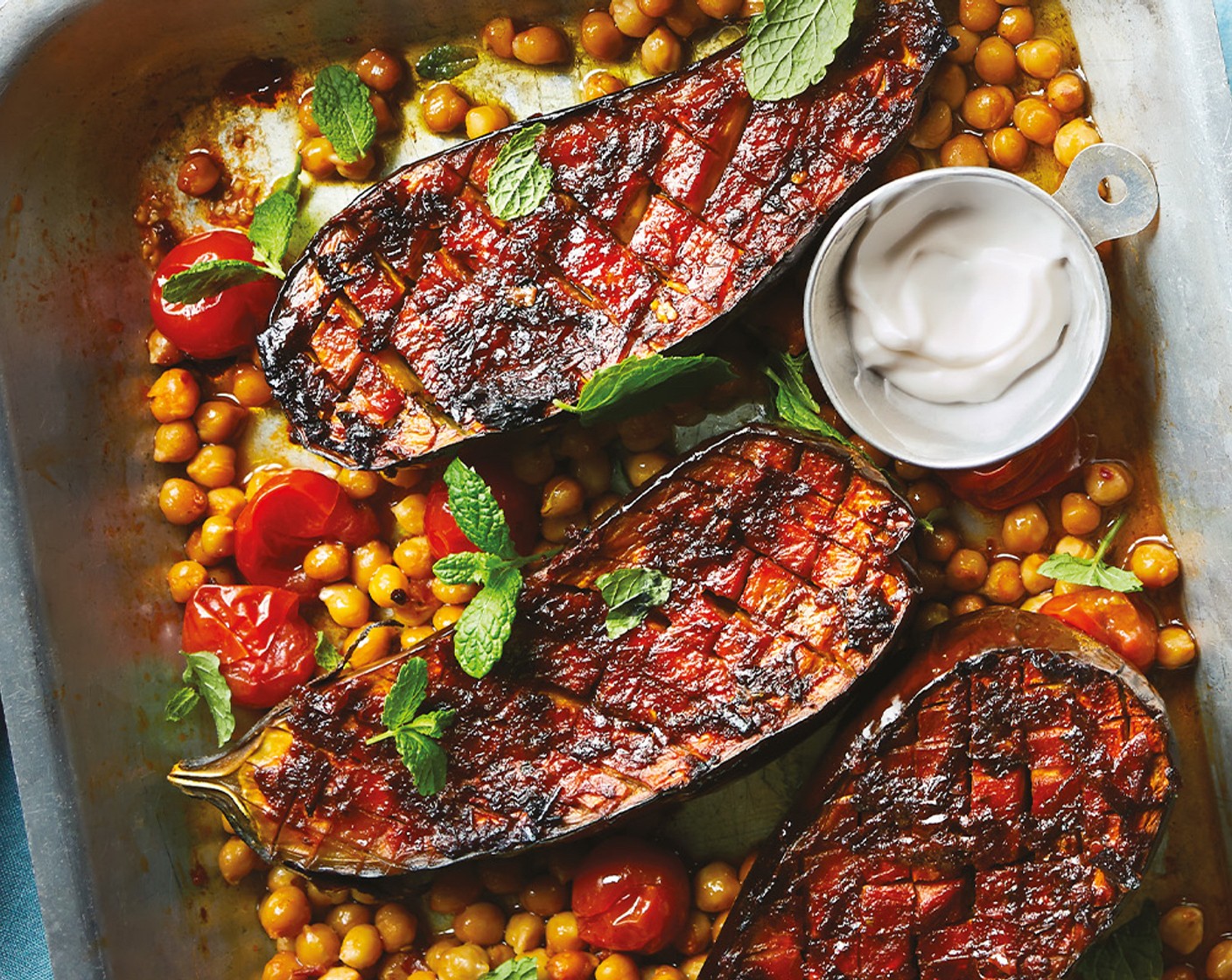 step 6 Divide the chickpeas and tomatoes between four plates, and place an aubergine half on top of each. Top each with a small spoonful of coconut pot (to taste), a handful of torn mint (1 bunch) and a scattering of pomegranate seeds (200 g).