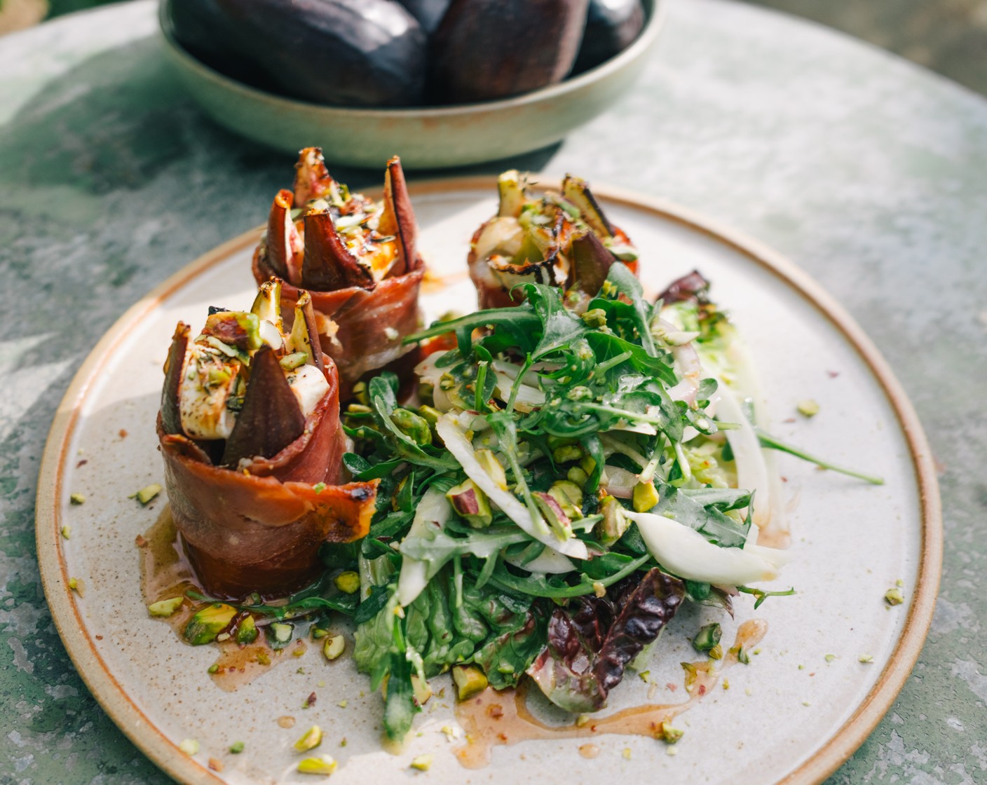 step 5 Remove the figs from the oven and discard the cocktail stick. Serve 3 figs onto each plate and add the salad alongside. Drizzle a little extra fig vinegar over the figs and sprinkle with pistachios (2 tbsp) to serve.