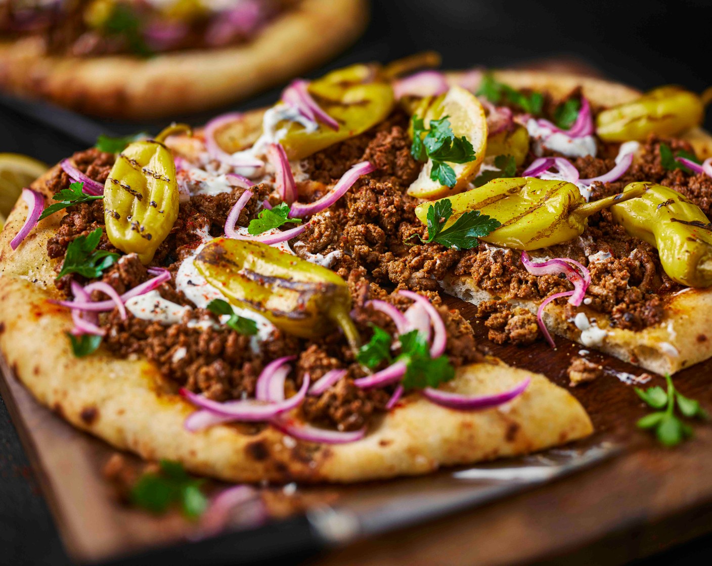 step 7 Top the baked flatbreads with the lemony onions, remaining parsley (12.5 g) and pepperoncini (5). Drizzle with yogurt (as needed) and serve with the remaining lemon (1), cut into wedges.