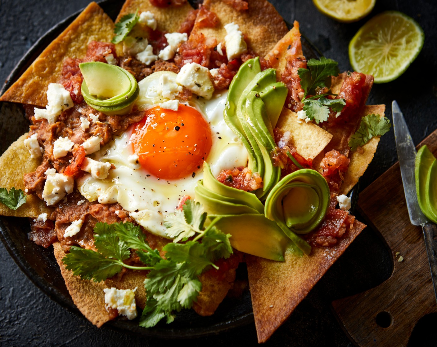 step 7 Briefly toss the tortillas in the red salsa and spoon into bowls. Top with the fried eggs, refried beans, crumbled feta (100 g), avocado (1) and fresh coriander (1 handful). Serve with the remaining lime (1), cut into wedges.