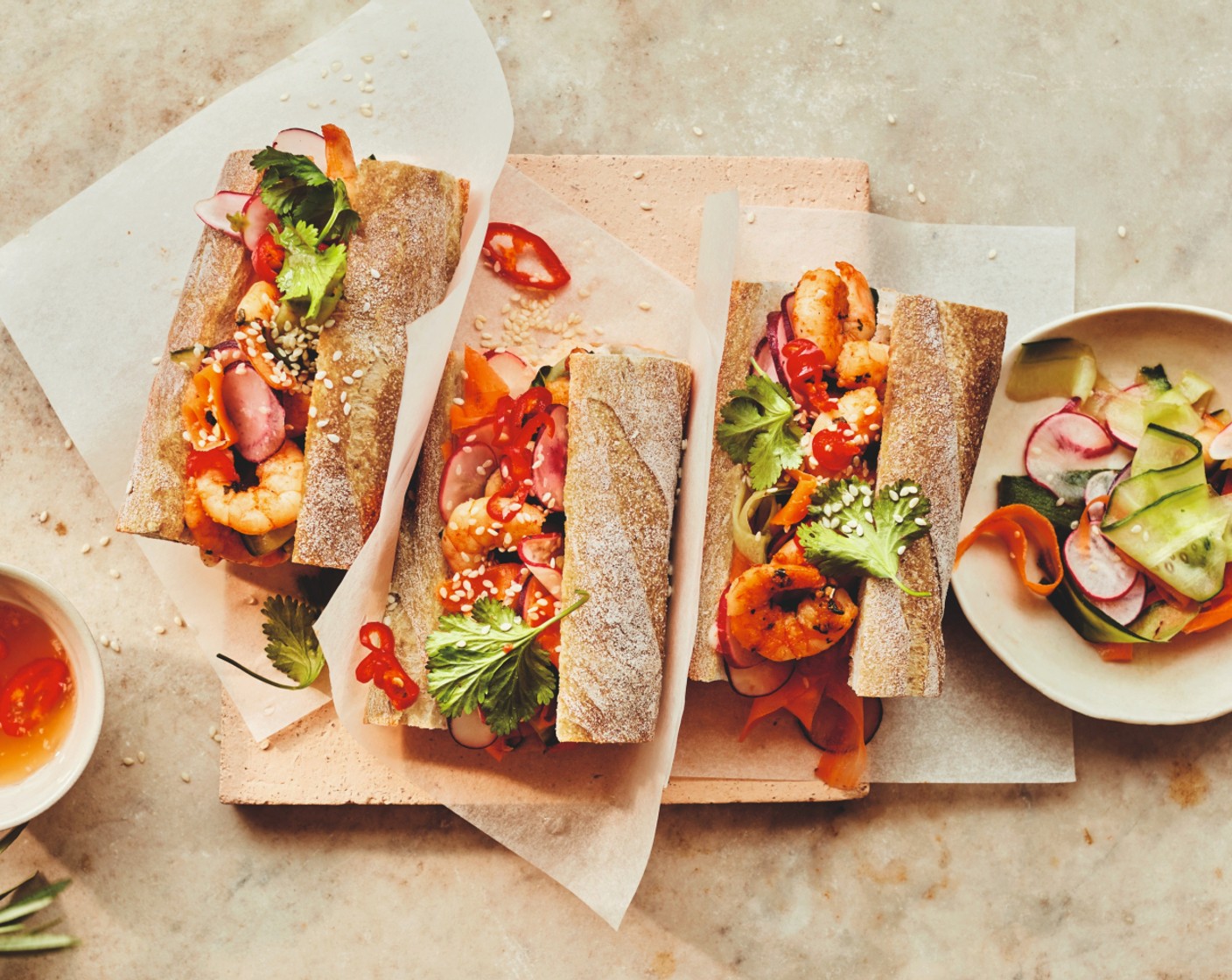 step 5 Cut the baguette (1) in half lengthwise and spread with the sriracha dressing. Pile in the pickled vegetables and prawns before spooning over the nuoc cham. Finish with the fresh coriander (1 handful) and sesame seeds (to taste), and serve with any leftover pickled veg.