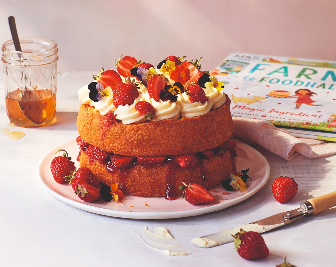 step 8 Carefully place the second cake on top of the first one. Cover the top of it with the honey buttercream and the remaining strawberries.