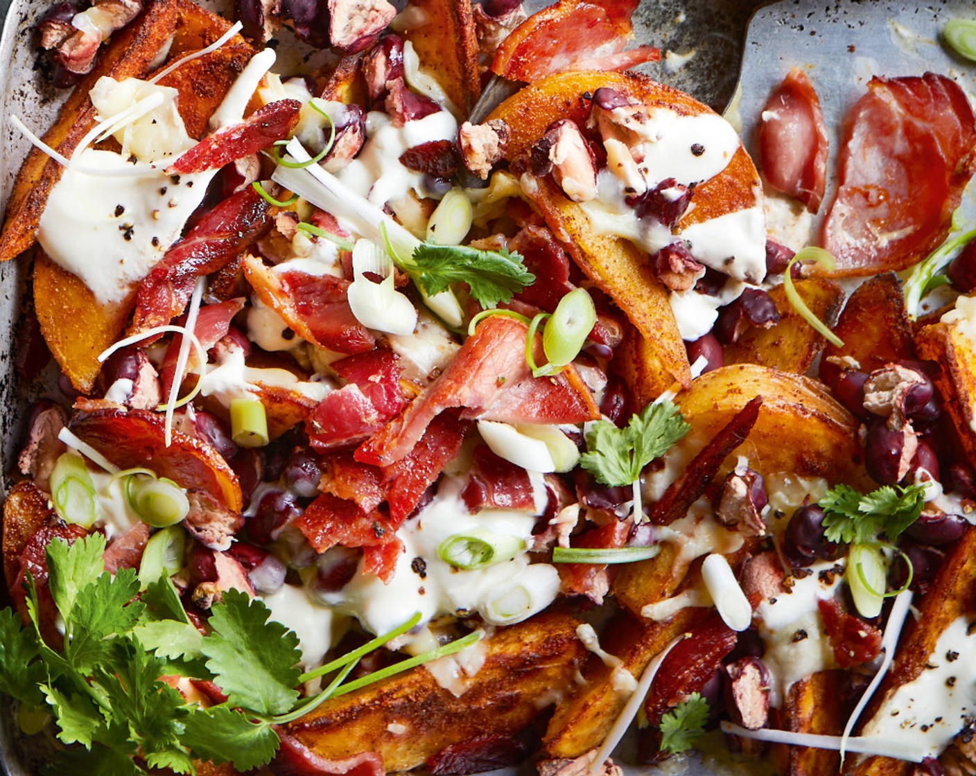 step 5 Break up the bacon into shards and scatter over the potatoes. Spoon over the soured cream (300 ml) and scatter over the salad onions (2) and coriander (1 handful).