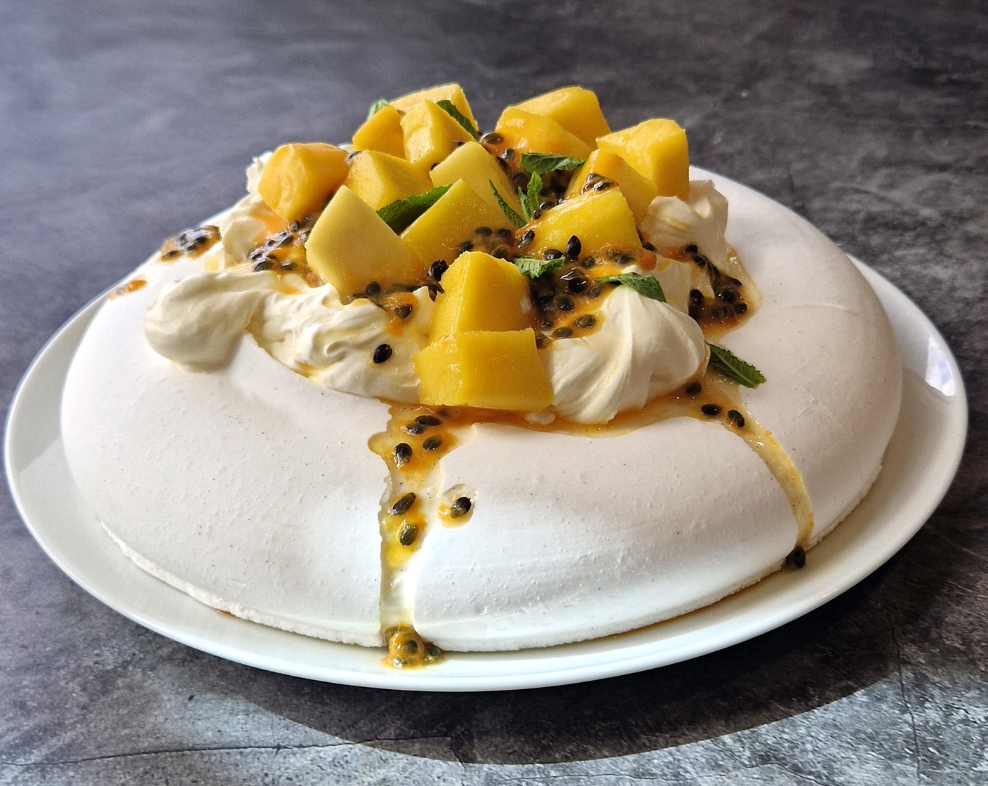 step 2 Pile the cream onto the M&S Collection Madagascan vanilla pavlova base (1) followed by the mango chunks (1/2 pack). Finish with M&S passion fruit pouch (1 pouch) and a scattering of mint (as needed).