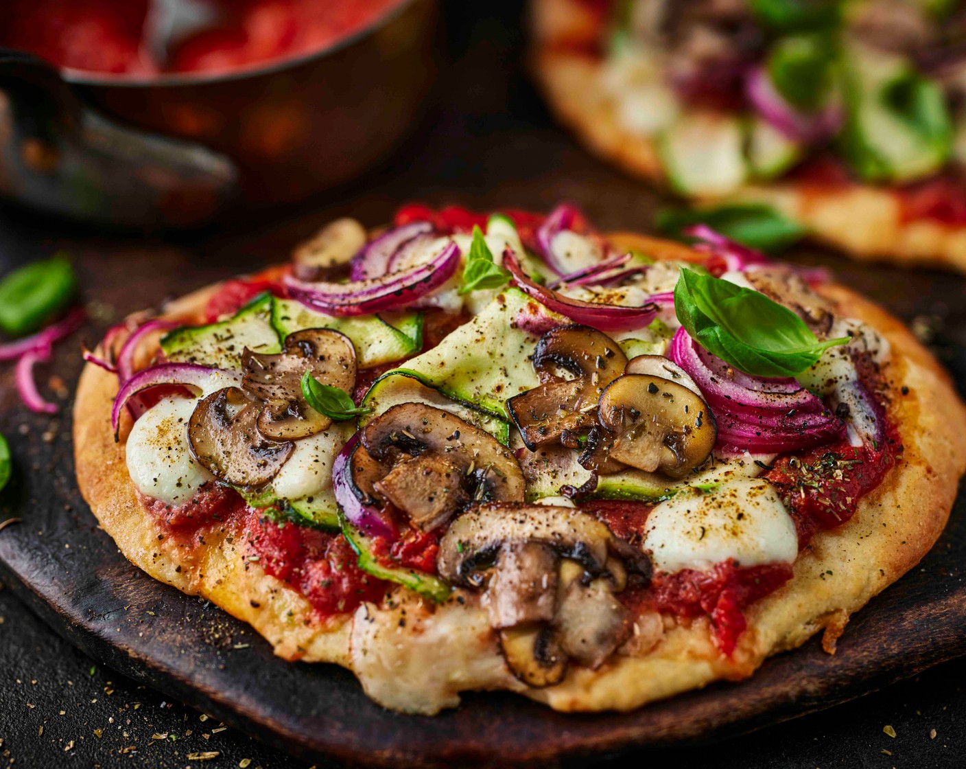 step 7 Top each with some of the tomato sauce, mushrooms (30 g), courgette ribbons (1/4) and red onions (1/4). Tear over the mozzarella (1). Season with salt and pepper and drizzle with a little more olive oil. Return to the oven for a further 5 minutes, until the cheese is golden and bubbling. Top with a scattering of basil leaves (1 handful) if you’d like.