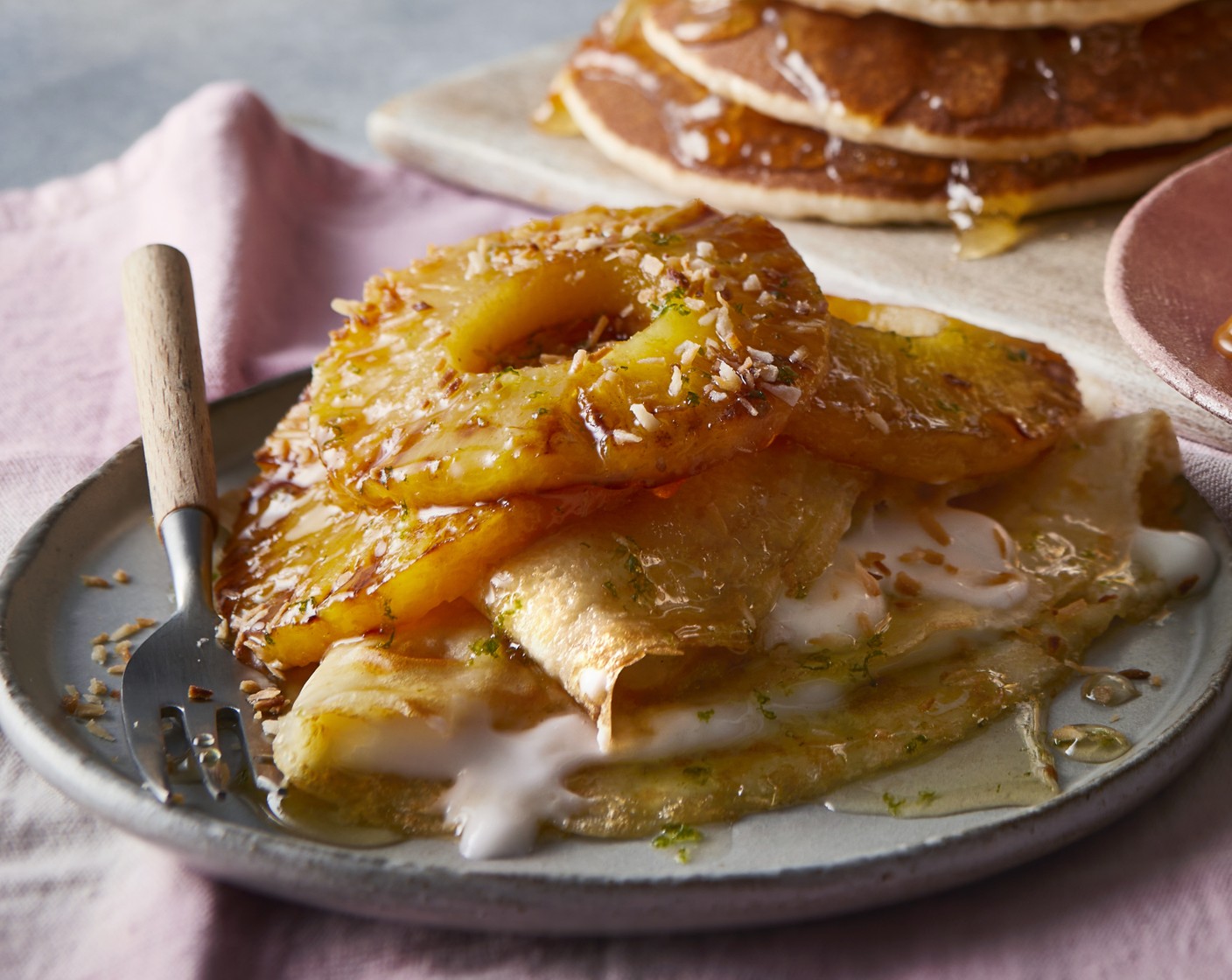 step 15 Top your cooked pancakes with the grilled pineapple slices, coconut pot (3 tbsp) and desiccated coconut (1 tbsp) sprinkled on at the end. Finish with a good drizzle of rum and pineapple syrup.