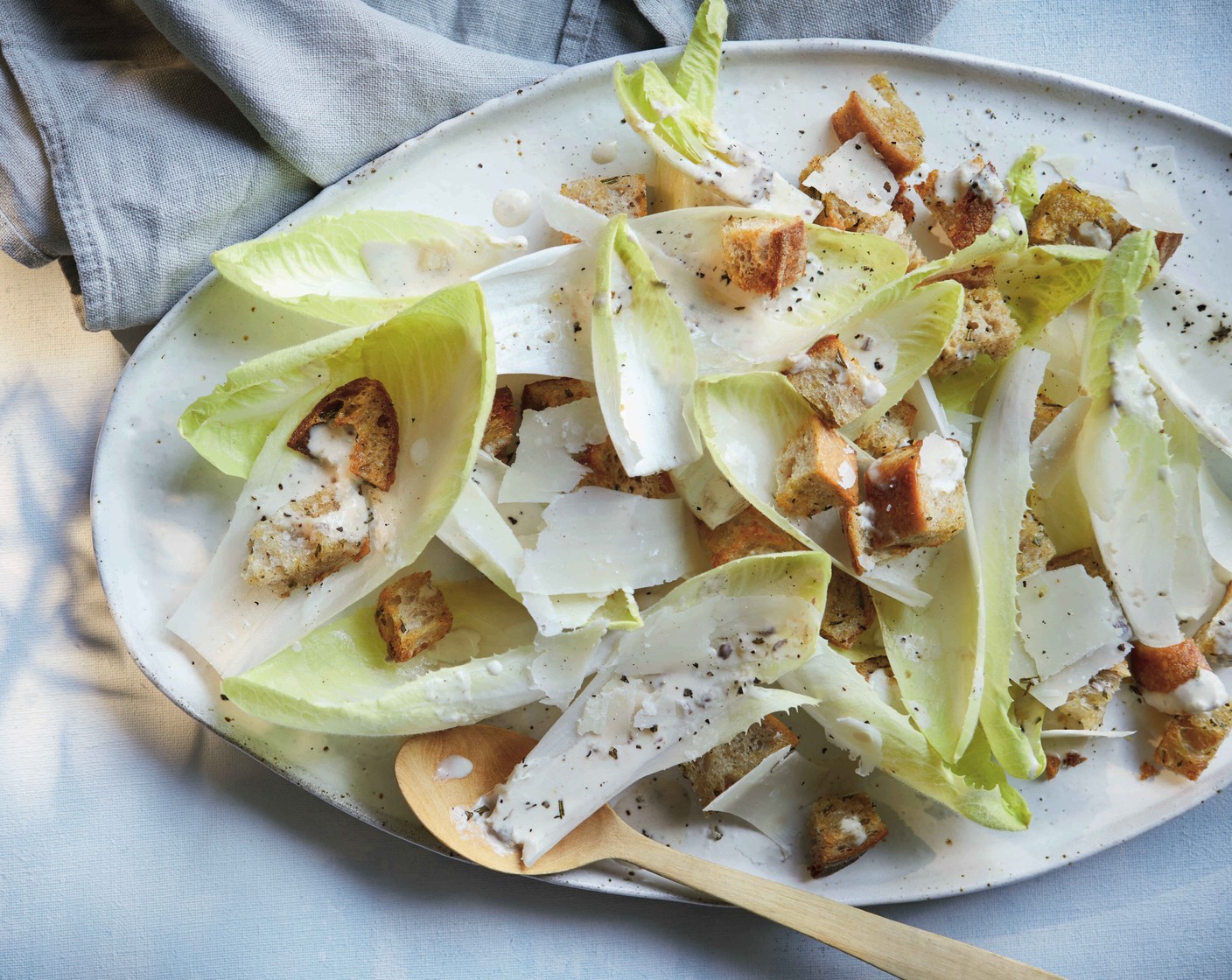step 6 Mix the chicory leaves (400 g) with ¾ of the dressing and arrange on a large serving platter. Top with the croutons, some parmesan shavings and the remaining dressing.