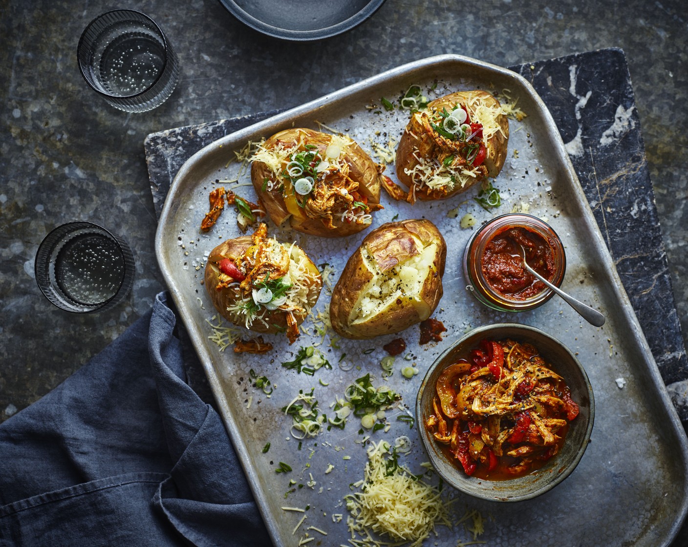 step 5 Cut the jacket potatoes in half and fill with the chicken and pepper mixture, then scatter a handful of the grated cheese (1/2 block) and spring onions (1 bunch) on top of each.