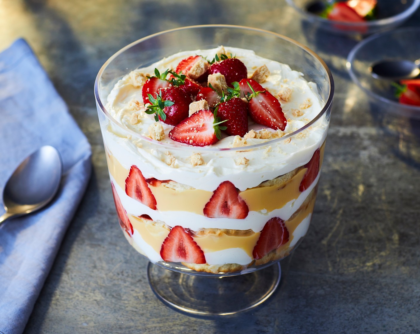 step 3 Whip the whipping cream (300 ml) with the icing sugar (2 tbsp) until soft peaks form. Spread the halves of scones (8) with the strawberry conserve (170 g) and place a layer at the bottom of your trifle dish. Scatter over some of the syrupy strawberries then spoon over a layer of custard (400 g) followed by a layer of cream. Repeat the layers before finishing with the remaining fresh King strawberries (200 g) and crumbling over the mini shortbread fingers (as needed) to serve. Spoon over any leftover strawberry syrup just before serving.