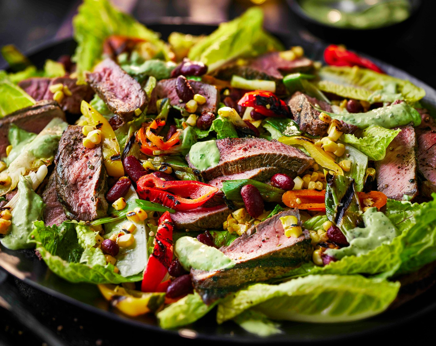 step 6 Slice the steak against the grain and lay it over the lettuce, followed by the charred veg and chipotle beans. Finish with the remaining dressing.