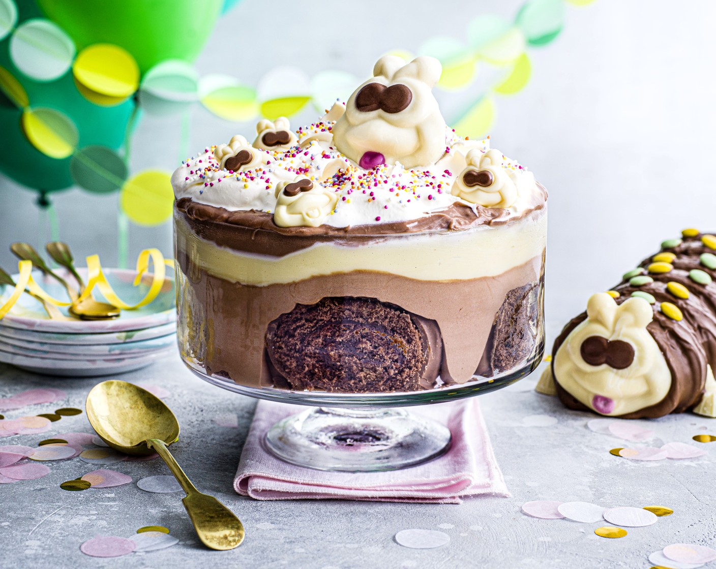 step 6 To decorate, beat the remaining 200ml whipped cream (2/3 tub) until fully whipped, spread evenly over the custard layer, smoothing out to the edges. Top with jazzie sprinkles (to taste), mini Colin faces (to taste) and the large Colin face (1).