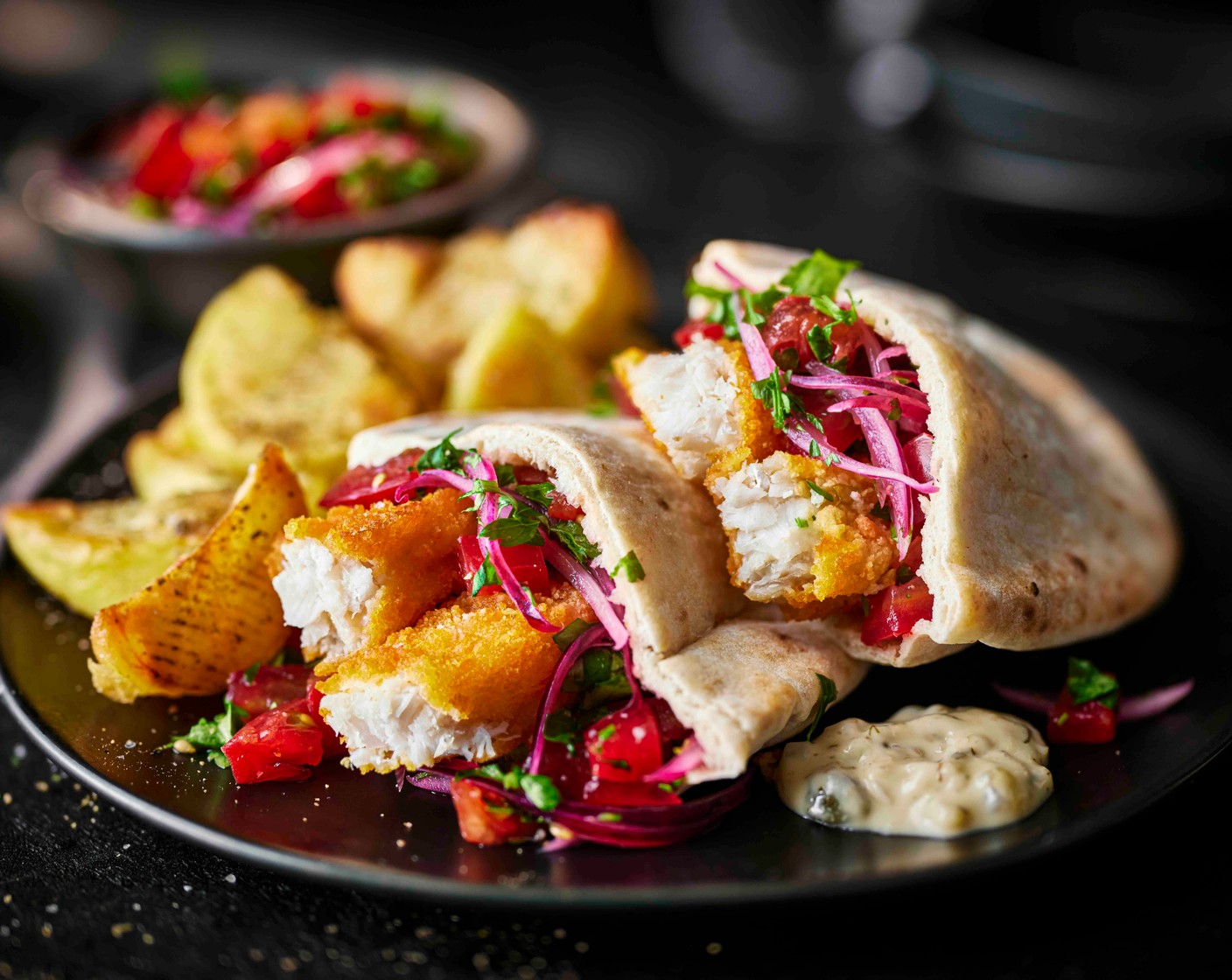 step 6 To serve, stuff each pitta with a spoonful of tartare sauce (100 g), the tomato and onion salad and the fish fingers. Serve with the seasoned wedges on the side.