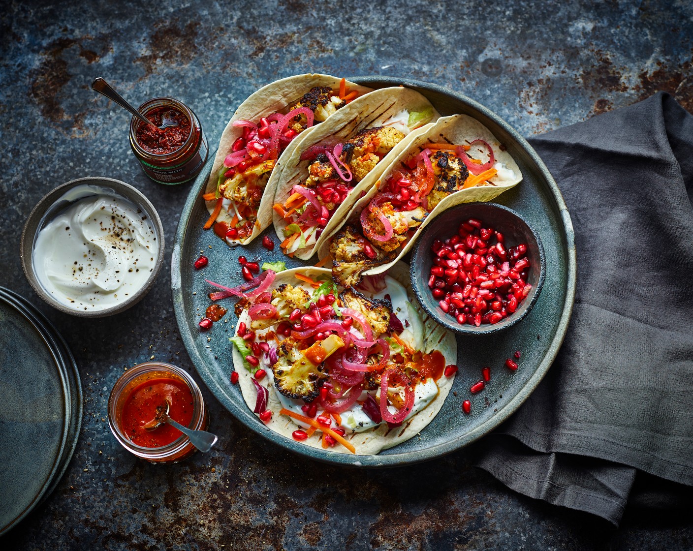step 6 To serve, spread some yogurt (to taste) onto each warm tortilla, top with a small handful of salad (to taste) and a few florets of roasted cauliflower. Drizzle with some harissa dressing, then scatter with pomegranate seeds (1 pack) and a few pickled red onions (to taste). Wrap up and enjoy!