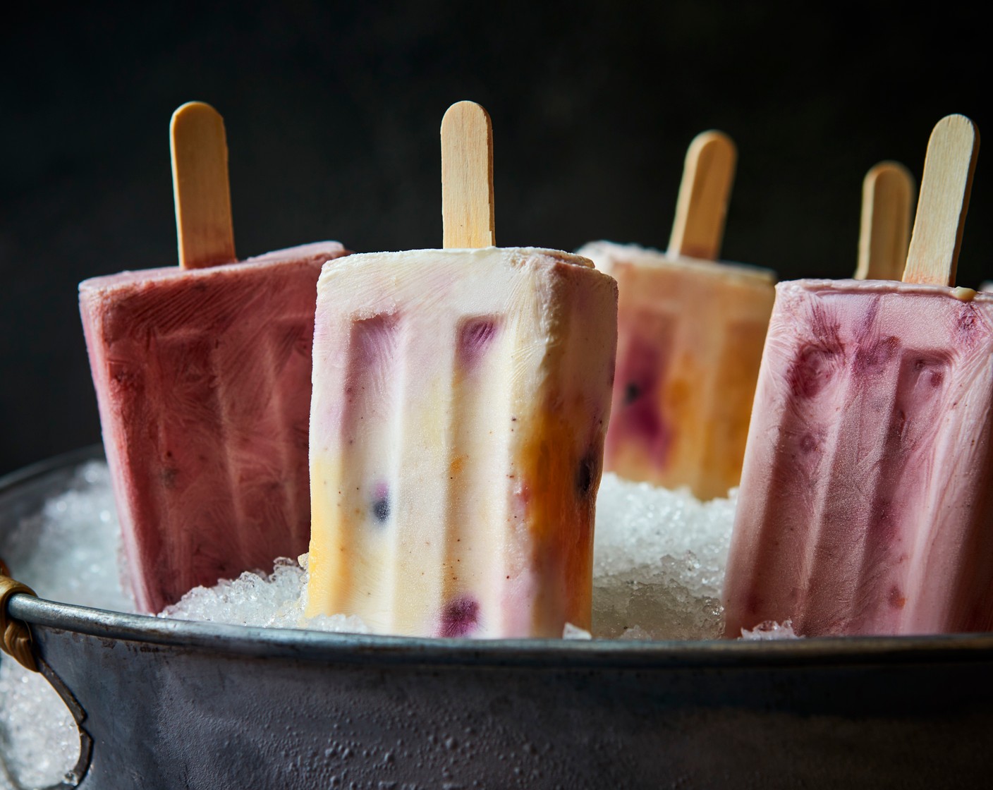 step 2 To make the cherry and raspberry lollies, divide the cherry yogurt (2 tubs) between the lolly moulds, then drop in the frozen raspberries (60 g), using a spoon to help evenly distribute them. Place in the freezer for at least 2 hours, or until frozen solid.