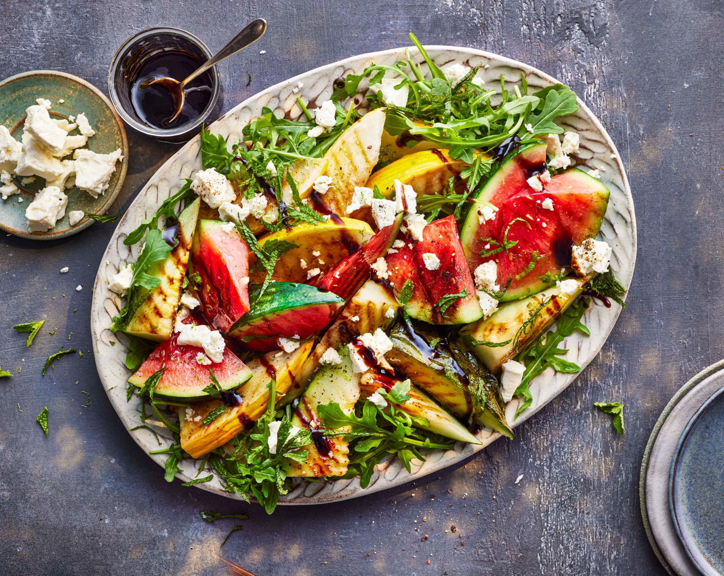 step 3 Add the rocket (60 g) to a serving platter and top with the melon, crumbled feta (100 g), mint (1 handful), a generous drizzle of balsamic glaze (to taste) and some pepper.