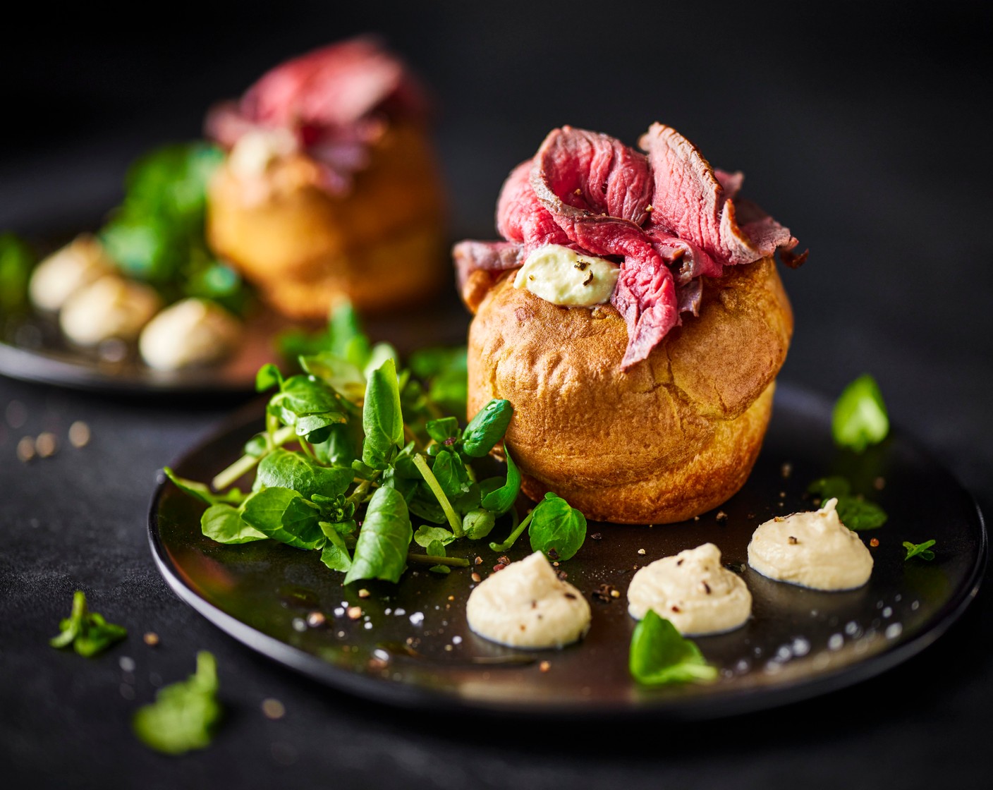 step 10 To assemble, place the cooled Yorkshire puddings on a serving platter. Slice each steak into 6 thin strips along the longest length, so you have 12 strips in total. Once sliced, roll each up into rosettes. Snip the tip of the piping bag and pipe a little horseradish cream into the bottom of each Yorkshire. Top the horseradish cream with a rosette of beef, then pipe another small dot of cream on top of the beef. Serve with a little dressed watercress.