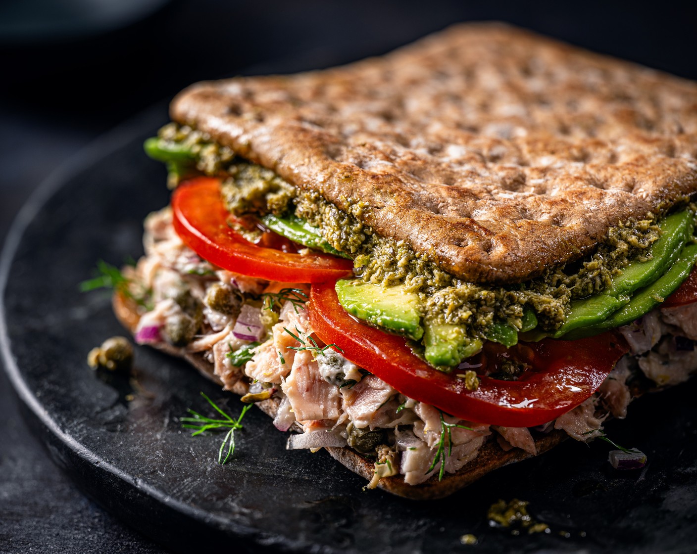 step 2 Toast the sandwich thins (4) and load up with the tuna, and top with the thinly sliced avocado (2), tomato (2) and spread the other side with pesto (4 tbsp) and squish together and slice in half.